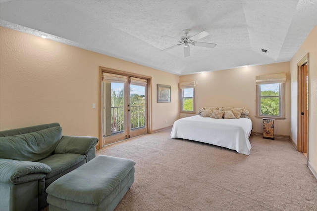 carpeted bedroom with ceiling fan, access to exterior, a textured ceiling, and multiple windows