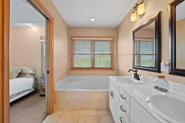 bathroom with vanity, a textured ceiling, and tiled tub