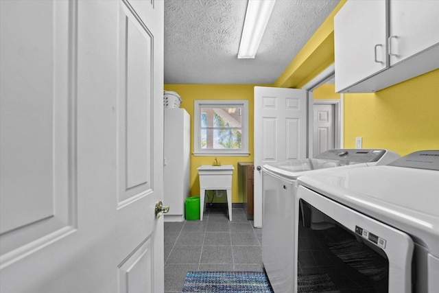 laundry room with washer and clothes dryer, cabinets, and a textured ceiling