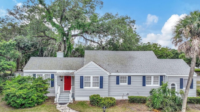 ranch-style home featuring a chimney and roof with shingles