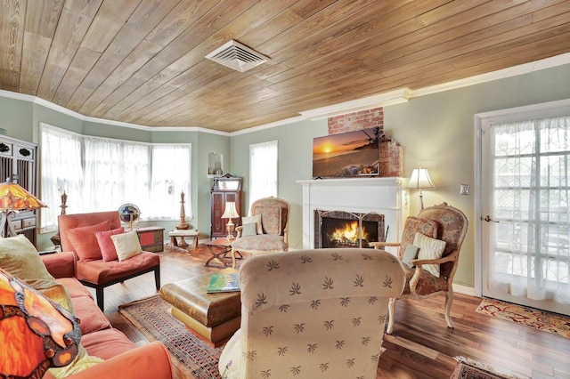 living area with wood ceiling, ornamental molding, a lit fireplace, and visible vents