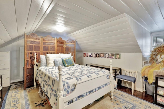 bedroom featuring wood-type flooring, wooden walls, and vaulted ceiling