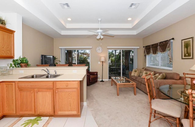 kitchen with light tile floors, sink, ceiling fan, and a raised ceiling