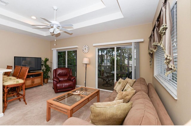 carpeted living room with a tray ceiling and ceiling fan