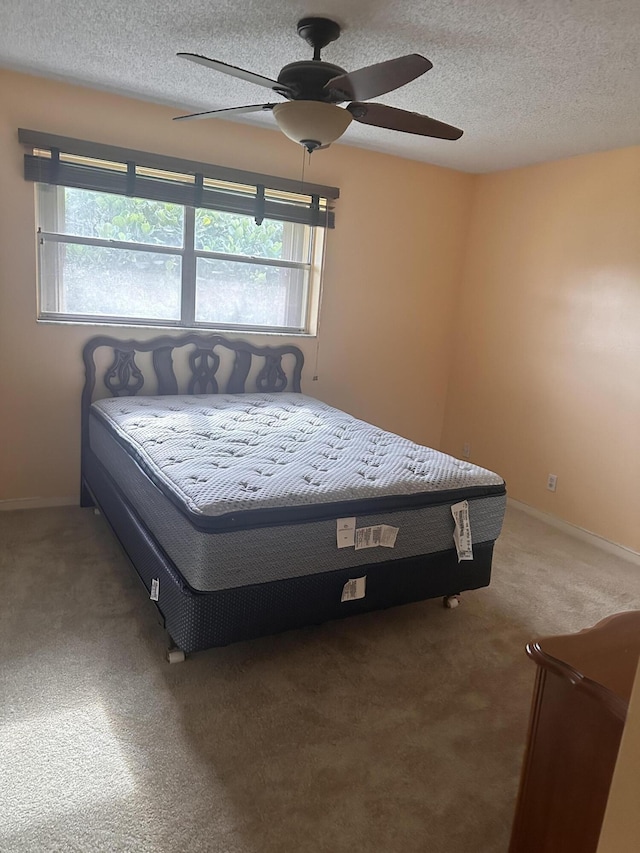 bedroom with a textured ceiling, ceiling fan, and carpet floors