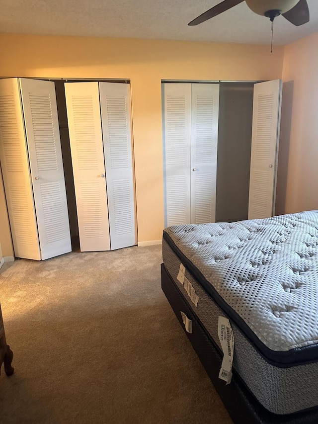 bedroom with ceiling fan, multiple closets, and carpet flooring