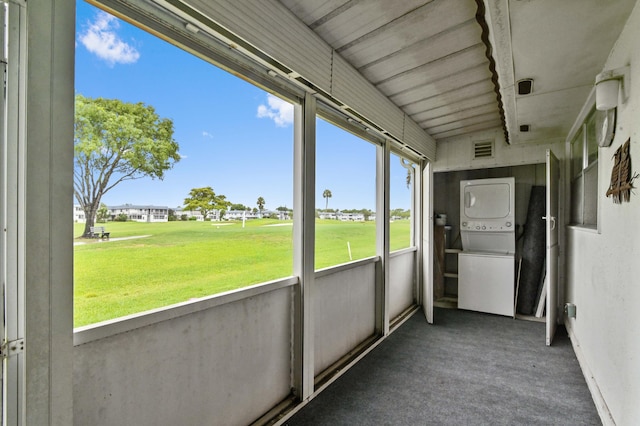 unfurnished sunroom featuring a healthy amount of sunlight and stacked washing maching and dryer