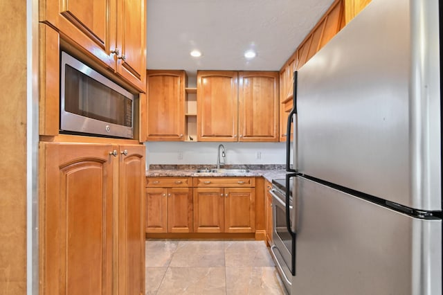 kitchen with light stone countertops, sink, and stainless steel appliances