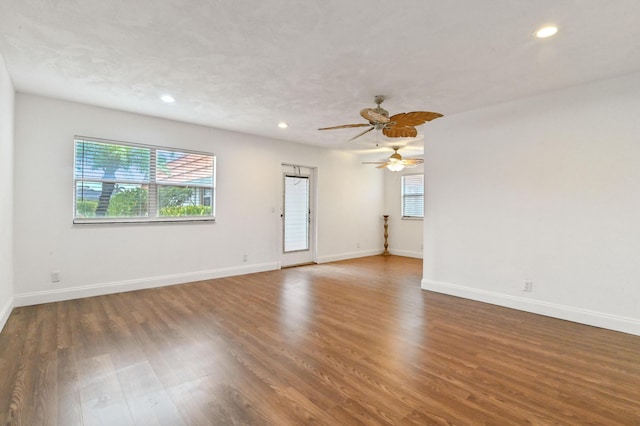 empty room featuring dark wood-type flooring, ceiling fan, and a healthy amount of sunlight