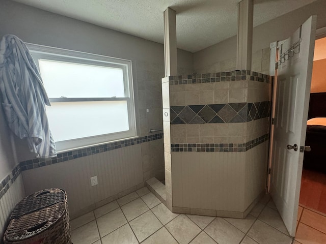 bathroom with tile flooring, tile walls, and a textured ceiling