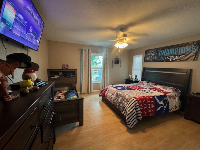 bedroom with light hardwood / wood-style floors, a textured ceiling, and ceiling fan