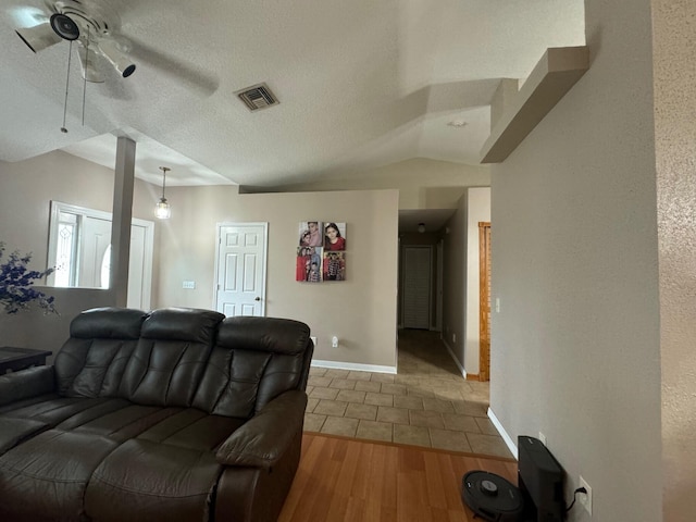 living room featuring lofted ceiling, a textured ceiling, ceiling fan, and light wood-type flooring