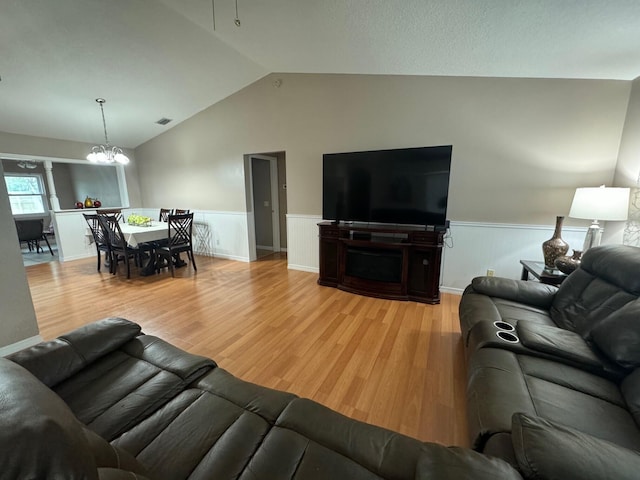 living room featuring a chandelier, vaulted ceiling, and light hardwood / wood-style flooring