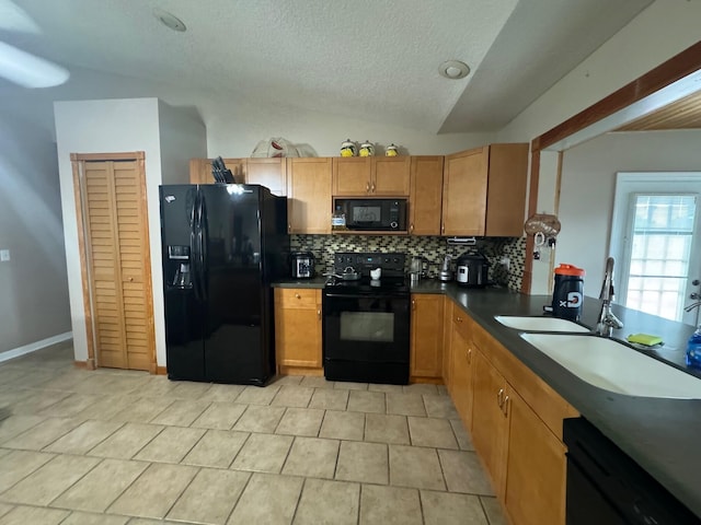 kitchen featuring black appliances, sink, tasteful backsplash, light tile flooring, and vaulted ceiling