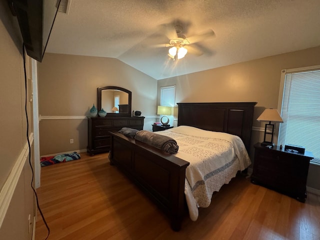 bedroom featuring ceiling fan, a textured ceiling, hardwood / wood-style flooring, and lofted ceiling