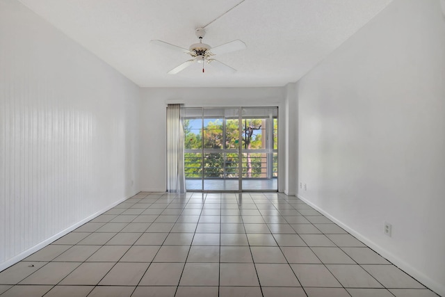 spare room with tile patterned flooring, ceiling fan, and wood walls