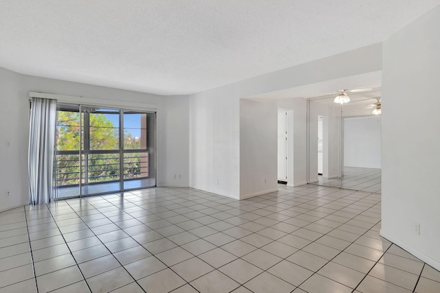 tiled empty room with ceiling fan and a textured ceiling