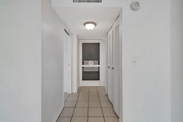 hall featuring light tile patterned floors and a textured ceiling