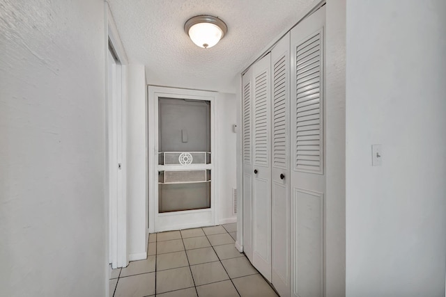 corridor with light tile patterned floors and a textured ceiling