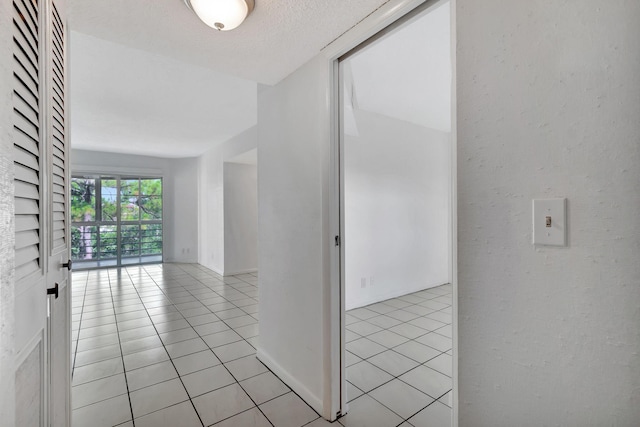 hallway featuring light tile patterned floors and a textured ceiling