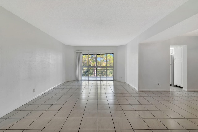 spare room featuring light tile patterned floors and a textured ceiling