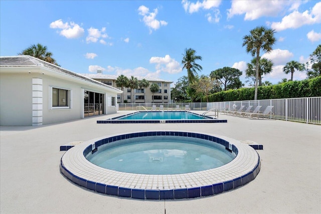 pool with fence, a community hot tub, and a patio