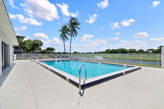 community pool with a patio area and fence