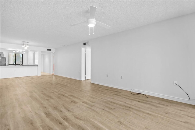 unfurnished living room featuring light wood-type flooring, visible vents, ceiling fan, and a textured ceiling