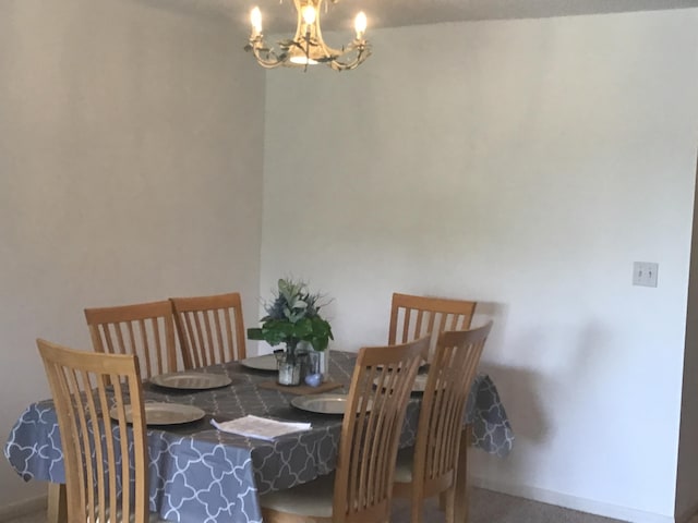 dining space with carpet flooring and an inviting chandelier