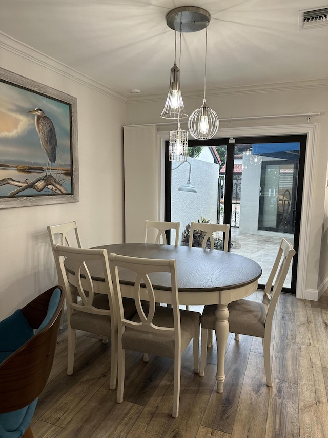 dining area with hardwood / wood-style floors, crown molding, and an inviting chandelier