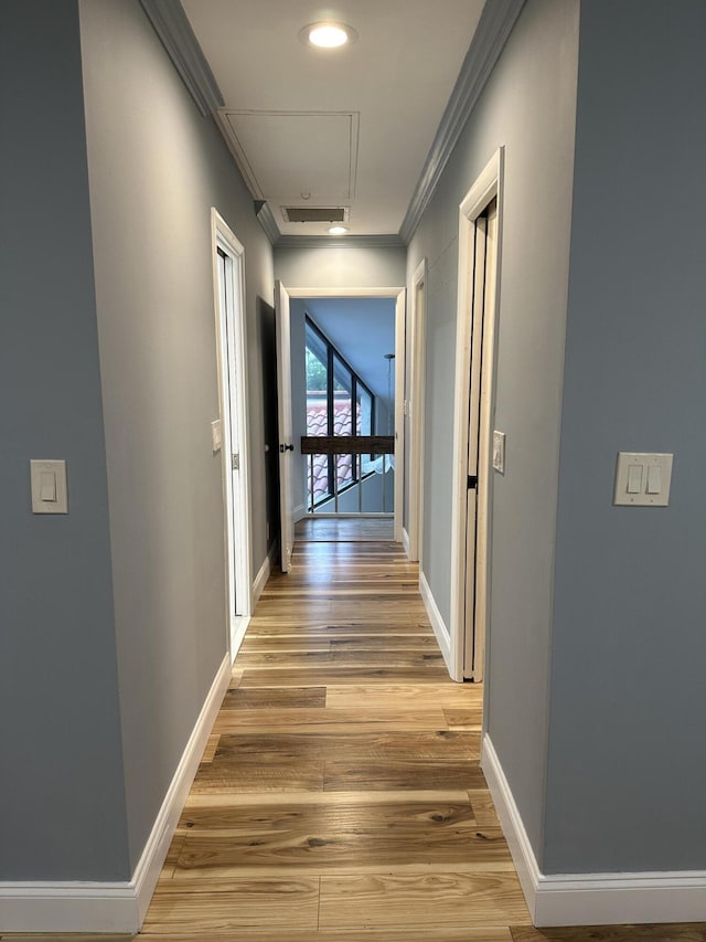 hallway with light hardwood / wood-style floors and ornamental molding