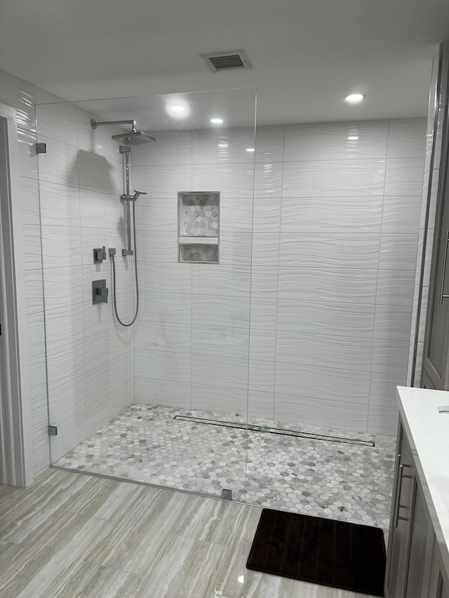 bathroom featuring a tile shower and vanity