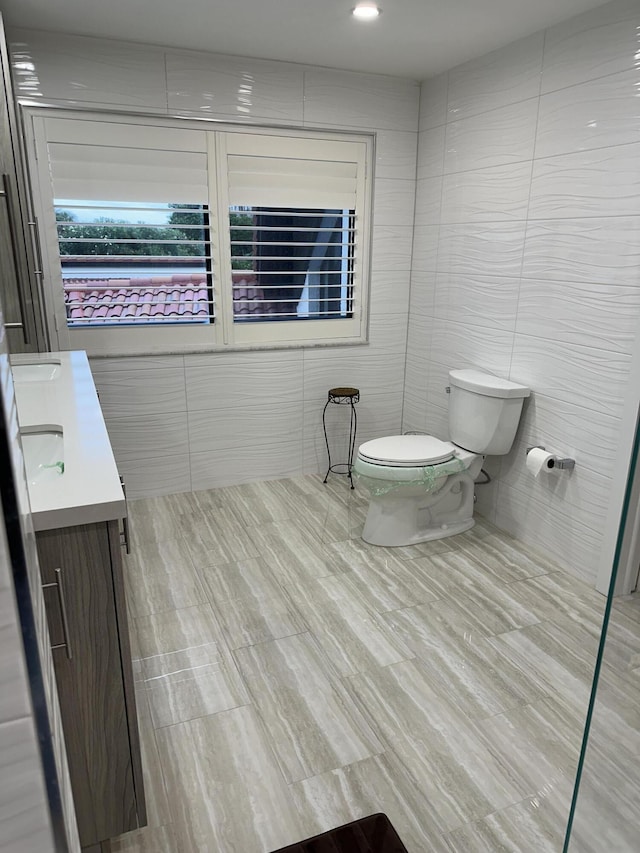 bathroom with vanity, toilet, and tile walls