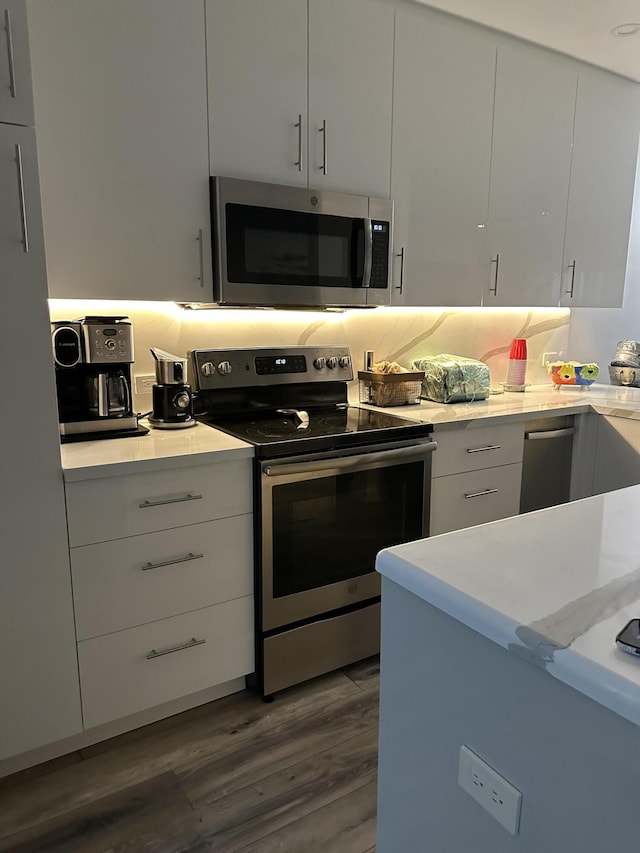 kitchen with white cabinets, appliances with stainless steel finishes, and dark hardwood / wood-style floors