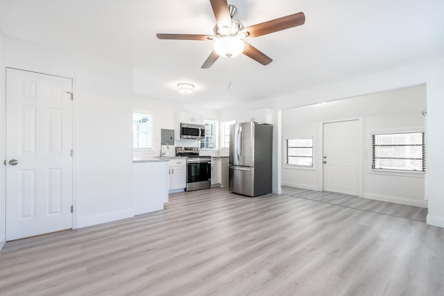 kitchen featuring stainless steel appliances, light hardwood / wood-style floors, plenty of natural light, white cabinetry, and ceiling fan