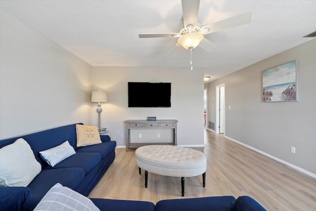 living room with light hardwood / wood-style floors, a textured ceiling, and ceiling fan