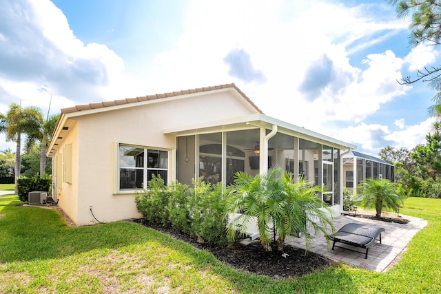 back of house with a lanai, central air condition unit, a patio area, a sunroom, and a lawn