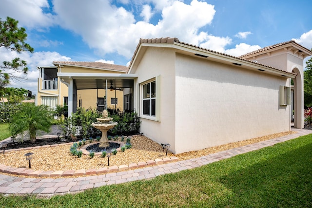 view of side of home featuring ceiling fan and a lawn