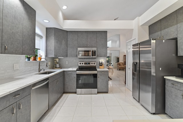 kitchen featuring sink, light stone counters, backsplash, light tile patterned flooring, and appliances with stainless steel finishes