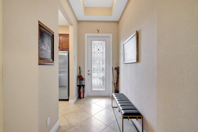 foyer with light tile patterned floors and a tray ceiling