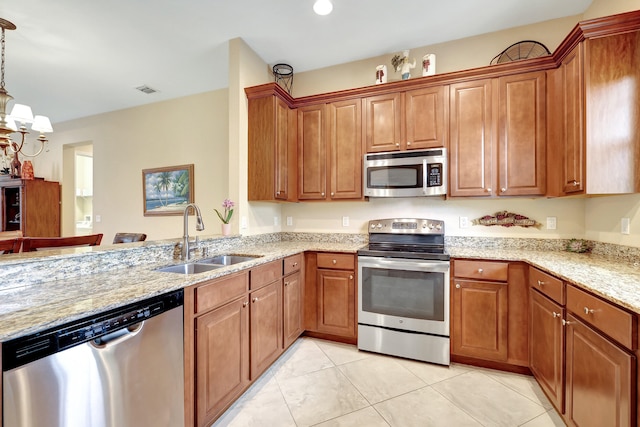 kitchen with decorative light fixtures, stainless steel appliances, light stone counters, sink, and light tile patterned flooring