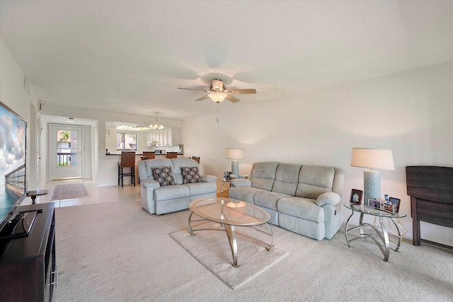 carpeted living room featuring ceiling fan with notable chandelier