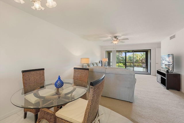 carpeted dining room with ceiling fan with notable chandelier