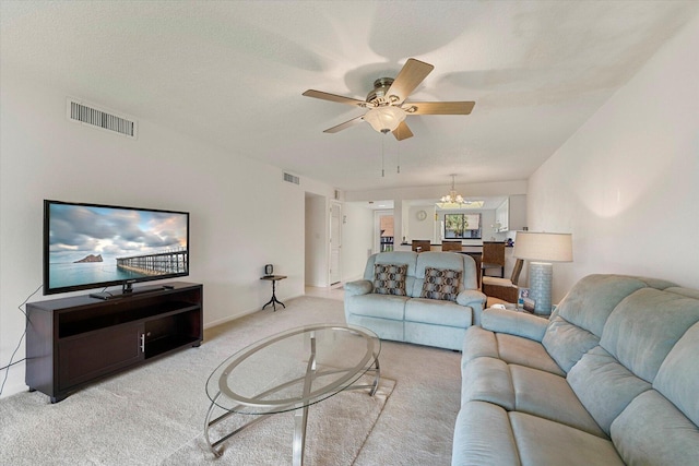 living room featuring a textured ceiling, light colored carpet, and ceiling fan with notable chandelier