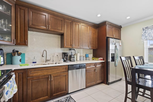 kitchen with appliances with stainless steel finishes, tasteful backsplash, crown molding, sink, and light tile patterned flooring