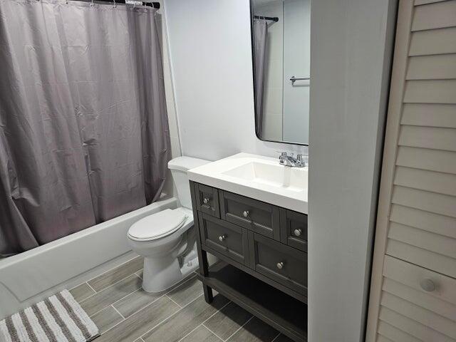 full bathroom featuring shower / bath combo with shower curtain, vanity, wood-type flooring, and toilet