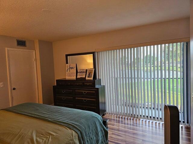 bedroom featuring multiple windows, wood-type flooring, and a textured ceiling