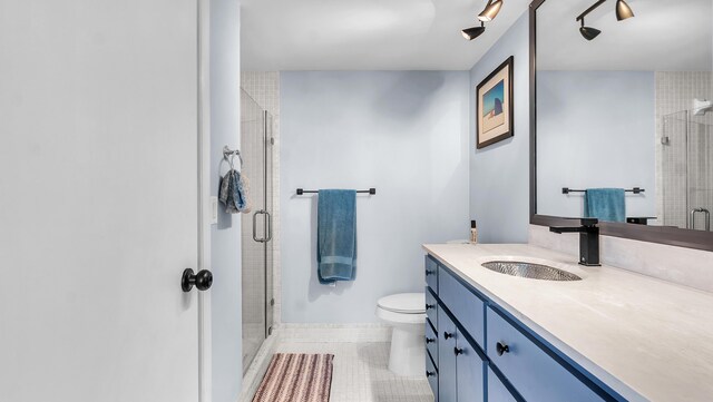 bathroom with a shower with shower door, tile flooring, oversized vanity, and toilet