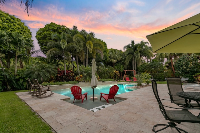 pool at dusk with a patio area