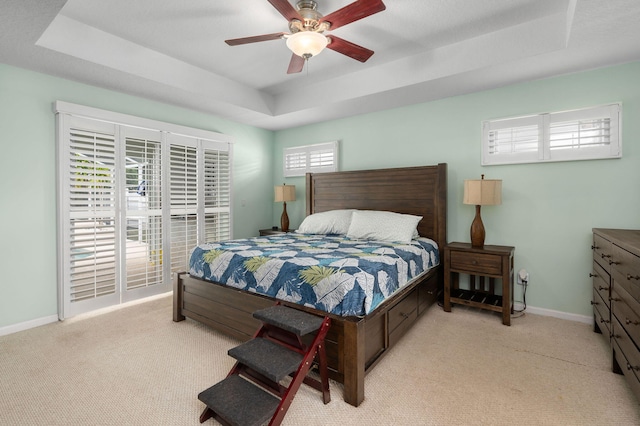 carpeted bedroom featuring a tray ceiling and ceiling fan